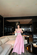 Woman in a pink dress standing in a modern living room.