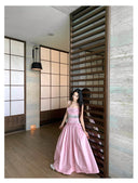 Woman in a pink dress standing in a modern interior setting with wooden panels and a light floor.