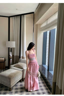Woman in a pink dress standing in a modern room with neutral decor.