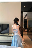 Woman in a light blue dress standing in a modern living room.