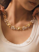 Gold necklace with pearls worn by a person, close-up shot.