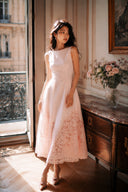 Luxury blush pink midi dress featuring intricate lace hem detail and elegant sleeveless design for formal occasions