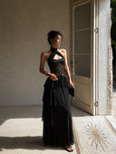 Side view of the Vogsion Nocturne black lace corset maxi dress featuring breathable layered ruffles, sheer lace detailing and a flattering silhouette for weddings, evening events and vacations.