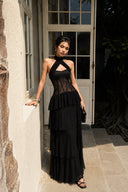 Editorial outdoor photo of the Vogsion Nocturne black lace ruffle maxi dress with a structured corset bodice, lightweight flowing skirt and timeless black formal styling.