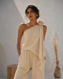 Portrait of a model in the VOGSION Élan Quiet Luxury Linen Set featuring a premium linen asymmetric top with statement floral shoulder and relaxed wide-leg trousers, perfect for luxury resort wear and timeless summer styling.