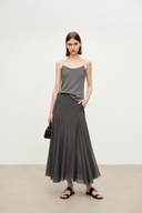 A woman modeling a dark gray sleeveless camisole top and matching VOGSION Celine High Waist Silk-Flow Maxi Skirt, styled with black sandals and a small black handbag against a plain light gray studio background.