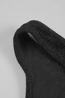 A close-up of a black VOGSION Noire Rosalie Glitter Rose Mermaid Maxi Dress, likely a strap or trim, with a glittery, sparkly finish and a smooth black inner lining, set against a plain light gray background.