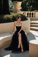 A woman wearing Vogsion Petite Structured Lace Corset Tulle Maxi Dress sits on a stone terrace in a garden setting.