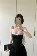 A woman takes a mirror selfie wearing a Vogsion Petite Structured Lace Corset Tulle Maxi Dress. She is holding a black clutch with the brand name 'CHANEL' visible on the front, and wearing a white shoulder bag.