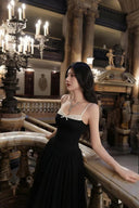 A woman wearing a Vogsion Petite Structured Lace Corset Tulle Maxi Dress stands on an ornate indoor balcony in a grand, candle-lit historic building.