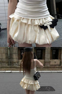 Model wearing a Y2K ivory bubble hem mini dress with built-in shorts and ruched cami bodice