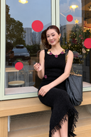 Long version of the black embellished fringe knit dress, shown seated by a window; this photo does not show the mini-length version.