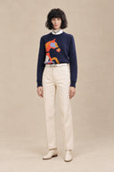 Cavelle navy horse intarsia crewneck sweater styled with cream trousers and ankle boots.
