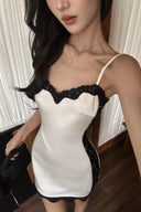 Close-up of the V-neckline and black lace trim on the ivory satin-finish dress