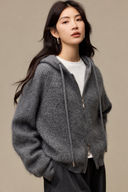 Angled front view of the Grey hooded cardigan styled over a white crewneck with black tailored trousers.