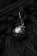 Close-up of a silver-tone engraved charm on the Noctara black lace maxi skirt