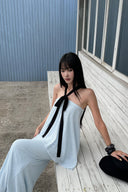 Seated view showing black halter tie and textured light blue top with matching maxi skirt