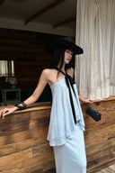 Close three-quarter view of light blue halter top with black tie and layered hem