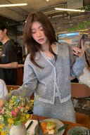 Petite woman wearing grey wool-blend faux-layer cardigan and A-line knit skirt set in a cafe