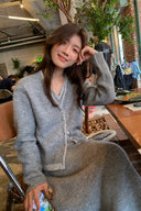 Petite model seated in the grey wool-blend faux-layer cardigan and long A-line knit skirt set
