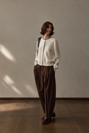 Angled full-length view of ivory wool cardigan with a dark shoulder bag