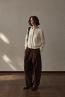 Ivory wool button-front cardigan styled with brown trousers in natural light