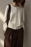 Close-up of ivory wool cardigan showing dark neckline trim, buttons and fine knit texture