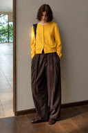 Yellow wool crewneck cardigan with front buttons and ribbed hem, styled with brown trousers