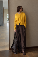 Full-length view of a yellow wool cardigan with a dark leather bag
