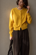 Close-up of yellow wool cardigan showing round neckline, buttons and ribbed hem