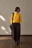 Yellow wool button-front cardigan on a model walking with a dark shoulder bag