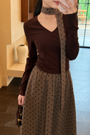 Close-up of the Odette chocolate V-neck knit top with a taupe polka dot maxi skirt and matching neck ribbon.