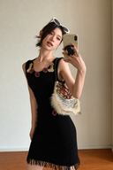 Black embellished knit mini dress with purple floral beadwork, gold-tone neckline accents and a fringed hem, styled with a sequined bag.