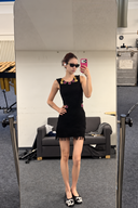Full-body mirror view of a black beaded knit mini dress with a fringed hem, styled with black flats.