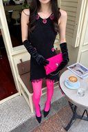 Black embellished fringe knit mini dress styled with pink tights, a pink clutch and long black gloves.