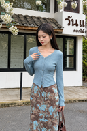 Petite model wearing a light blue ribbed cardigan with a brown floral maxi skirt