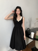 Black cotton knit midi dress with ivory rosette collar and gathered A-line skirt, model front view.