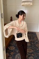 Ivory cowl-neck sweater with roomy batwing sleeves and rabbit-fur cuffs, worn with brown trousers and a black mini bag