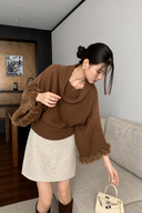 Brown cowl-neck batwing sweater with a gathered knit silhouette and rabbit-fur sleeve trim, worn with an ivory mini skirt