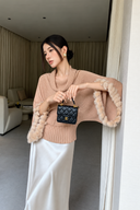 Blush cowl-neck batwing sweater with rabbit-fur cuffs, an ivory satin maxi skirt and a black structured mini bag
