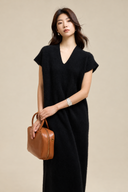 Black V-neck wool-blend knit dress worn on its own with a silver bracelet and tan leather bag.