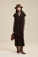 Full-length front view of the brown V-neck knit dress styled with a hat, brown boots and suede bag.