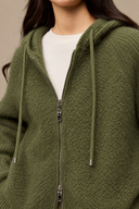 Close-up of the Sage Green cardigan showing textured knit, brushed fibres, hood drawstrings and silver-tone zipper.