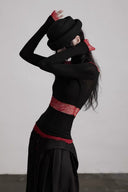 Side view showing the fitted black body, burgundy lace waist panel and loose hand-covering cuffs