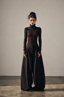 Front view of the regular-length black and red gothic mesh top styled with wide-leg pants