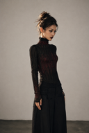 Model wearing the VOGSION Veinshade black and red gothic mesh top in regular length, three-quarter view