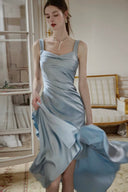 Dusty blue satin wedding guest midi dress with flowing asymmetric ruffle hem