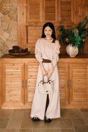 Petite model wearing the Almond VOGSION Amélie boat-neck cotton top and high-waist wide-leg pants set