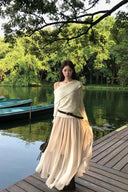 Apricot off-shoulder knit sweater layered over a khaki petite maxi dress by a lakeside