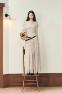 Apricot off-shoulder knit sweater styled over a khaki petite maxi dress in a neutral interior